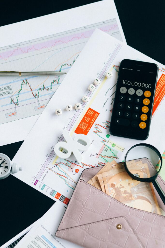 Flat lay of financial charts, smartphone calculator, and documents for market analysis.